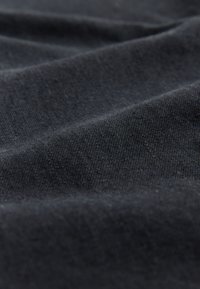 Schwarzer Stoff mit glatter Textur, der feine Falten und Knicke zeigt und die weichen, flexiblen Materialeigenschaften hervorhebt.