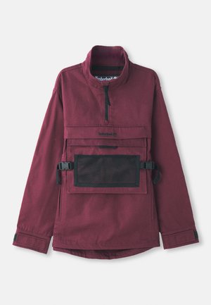 Burgundská pulóverová bunda s vysokým golierom, čiernou sieťovou vreckom na hrudi, nastaviteľnými čiernymi popruhmi a elastickými manžetami. Odolná textúra látky.