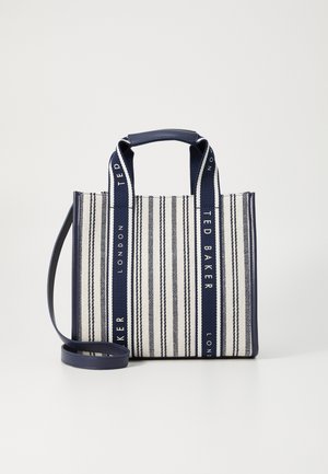 Torba typu tote w paski w kolorach granatowym i białym, wykonana z tkaniny, z dwoma krótkimi uchwytami oraz regulowanym paskiem na ramię z detalem w postaci logo.