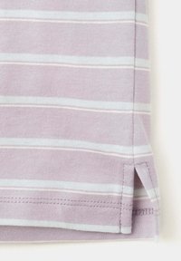 Tissu violet clair avec des rayures horizontales blanches montrant un ourlet avec une fente latérale et un détail de couture visible.