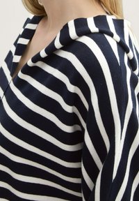 Marineblau-weiß gestreifter Pullover mit Kapuze, im lässigen Schnitt und weichem Strickmaterial. Sichtbare Nähte und ein V-Ausschnitt-Detail.