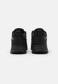 Svarta löparskor med övre i slät läder och mocka, vadderad krage och dämpad sula, som har en strömlinjeformad design och subtil märkning.