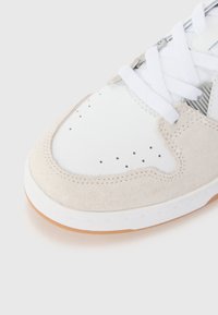 Hvide læder- og beige ruskinds sneakers med perforeret tå, hvide snørebånd og en gummigummisål. Har stitched detaljer og mesh accenter.