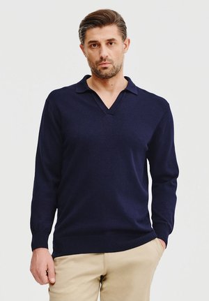 Granatowy sweter typu pullover z długim rękawem i dekoltem w kształcie litery V, o miękkiej fakturze, charakteryzujący się minimalistycznym wzornictwem oraz ściągaczami przy mankietach i u dołu.