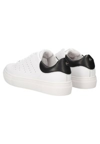 Sneakers bianchi in pelle con una texture liscia, impreziositi da un'accaento in pelle nera sul tallone e piccole perforazioni lungo i lati.