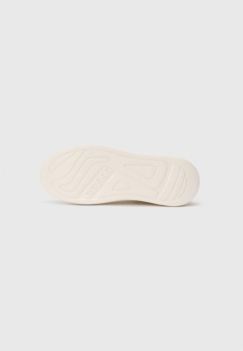 Suela de zapato blanca con diseños en los surcos y el nombre de la marca "GUESS" grabado en el centro, mostrado sobre un fondo liso.