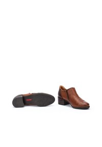 Chaussures à talons en cuir marron avec une texture lisse, présentant un bout arrondi, une insertion élastique sur les côtés et une semelle extérieure en caoutchouc à motifs.