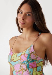 Multicolored swimwear with a geometric pattern in pink, green, and blue; features gold hardware accents on shoulder straps.