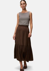 Gestreiftes ärmelloses Top, kombiniert mit einem fließenden braunen Maxirock mit gerafftem Taillenbund und gestuften Saum. Eleganter und leichter Stoff.