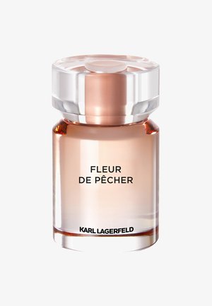 Klarer Glasparfümflakon mit einem runden, transparenten Deckel. Enthält eine blassrosa Flüssigkeit. Das Etikett lautet "FLEUR DE PÊCHER" und "KARL LAGERFELD."