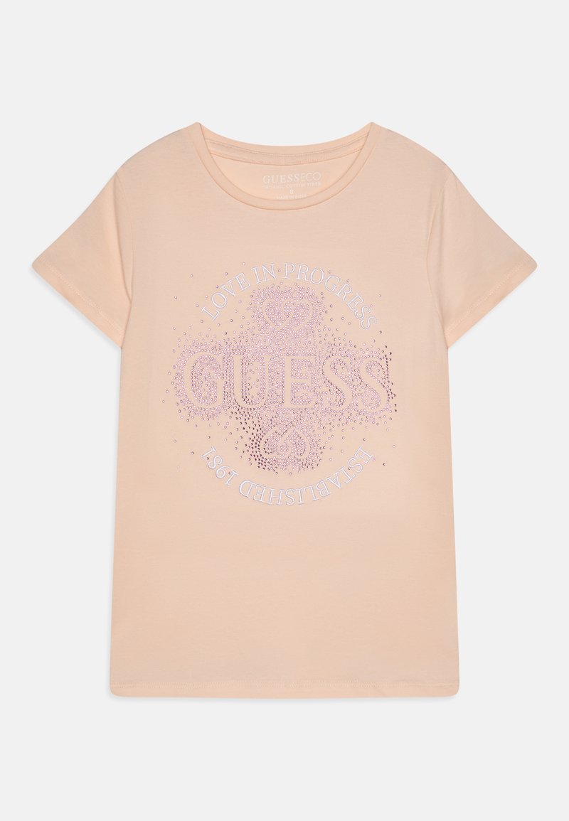 Peachfarget bomull t-skjorte, rund hals, korte ermer, med pynt i rhinestener som viser "GUESS" og "LOVE IN PROGRESS".