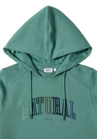 Zelená mikina s kapucí, zdobená textem "NATURAL" v vícebarevné výšivce. Vyrobena z měkkého materiálu s viditelnými švy.