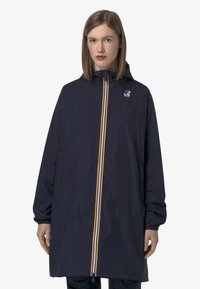 Veste de pluie marine à coupe longue, avec une fermeture éclair à l'avant et des rayures jaunes et blanches, ainsi qu'un logo sur la poitrine gauche.