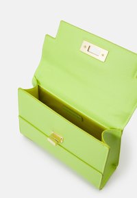 Groene gestructureerde handtas met een gouden gesp. Het interieur is glad en contrasterend geel. Heeft een gestructureerde vorm en een ruim compartiment.