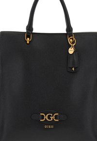 Borsa a tracolla nera in pelle con superficie testurizzata, dettagli in metallo dorato e un logo prominente. Presenta due manici e un'etichetta piccola.
