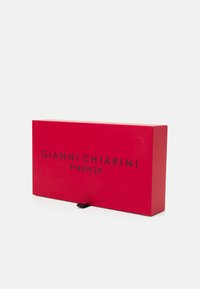 Röd papperslåda med magnetiskt stängning, med den präglade texten "GIANNI CHIARINI FIRENZE" i svart på framsidan.