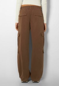 Bruine cargobroek met een relaxte pasvorm, voorzien van een elastische tailleband, twee zijcargopockets en twee achterzakken.