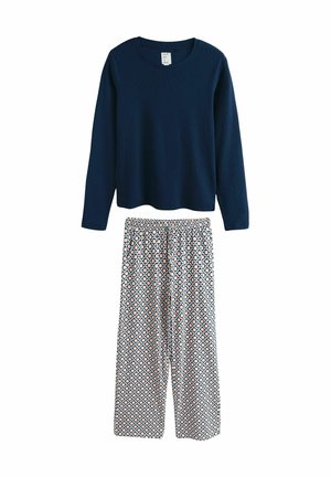Marineblaues Langarmoberteil mit geripptem Muster, kombiniert mit weit geschnittenen Schlafanzughosen mit geometrischen Formen in Pastellfarben.