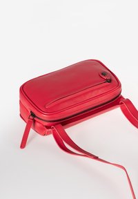 Rode leren schoudertas met een rechthoekige vorm, platte ritszak aan de voorkant en dubbele banden. Gladde textuur en minimale hardware.