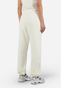 Crème kleurige sweatpants met een relaxed fit, voorzien van een elastische tailleband en boorden. G.combineerd met witte sneakers met zwarte accenten.