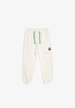Un pantalon de survêtement couleur crème présente une taille élastique avec un cordon turquoise, des poches latérales et des coutures turquoise contrastantes.