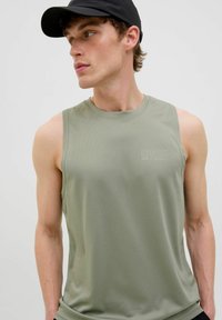 T-shirt de sport sans manches en vert olive clair, fait d'un tissu texturé. Présente un col rond et un logo discret sur la poitrine.