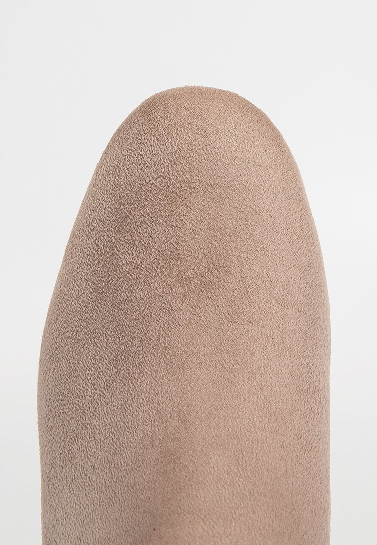 Suède enkelboot in licht taupe, met een gladde textuur en een rond neuzenontwerp. Schone lijnen zonder zichtbare hardware of accenten.