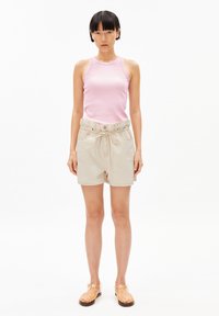 Light pink ribbed tank top with beige drawstring shorts; shorts feature side pockets and a relaxed fit. Tan strappy sandals complete the look.