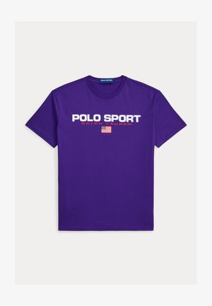 Tricou mov din bumbac cu inscripțiile „POLO SPORT” și „RALPH LAUREN” în text alb și roșu, cu un grafic al steagului american centrat dedesubt.