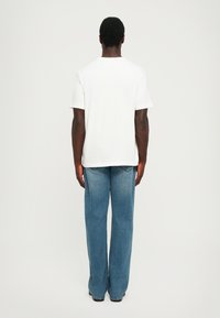 Tricou alb cu mânecă scurtă, asortat cu blugi largi de culoare bleu deschis. Material din bumbac, croială relaxată, design minimalistic fără modele vizibile.