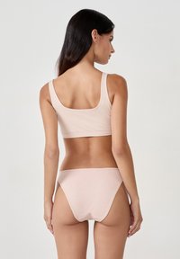 Set da notte in cotone rosa chiaro composto da un top cropped con spalline larghe e slip a vita bassa abbinati, con una texture morbida e cuciture minime.