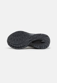Black athletic shoe sole with deep tread patterns and textured accents. Features a rounded heel and a flexible arch for traction and support.