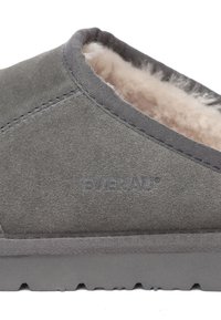 Grauer Wildlederschuh mit plüschigem Innenfutter, niedriger Profilierung und Gummisohle. Verfügt über gestickte Kanten und ein geprägtes Logo an der Seite.