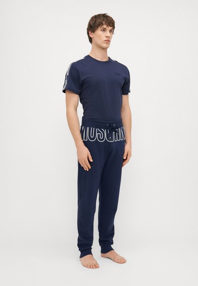 Námornícky bavlnený T-shirt s krátkymi rukávmi a logom; zodpovedajúce námornícke tepláky s šnúrkou a výrazným logom v páse. Hladká textúra.