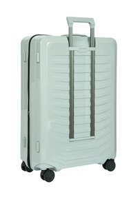 Hartschalenkoffer in hellgrün mit gerippter Textur; verfügt über einen Teleskopgriff und vier schwarze Rollen für gute Mobilität.