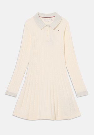 Kötött, krémszínű, hosszú ujjú ruha világosszürke gallérral, gombos kivágással és bordázott alsó résszel. Kis logo található a mellkason.