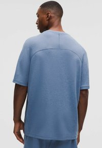 Kortærmet blå T-shirt, lavet af struktureret stof. Har en rund halsudskæring og en afslappet pasform med en diskret sømdetail på bagsiden.