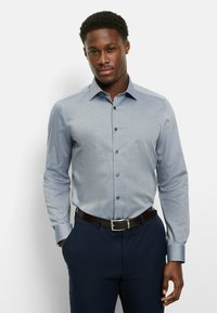 Light blue button-up shirt with a subtle pattern, long sleeves, and a collar. Paired with dark navy pants and a black belt.
