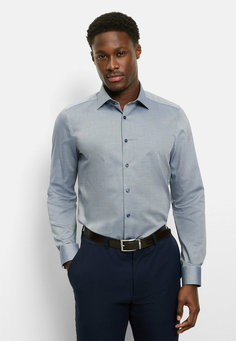 Light blue button-up shirt with a subtle pattern, long sleeves, and a collar. Paired with dark navy pants and a black belt.