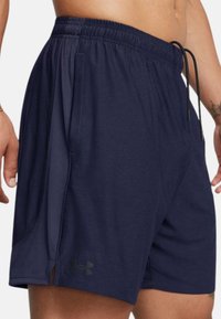 Navy athletic shorts made from breathable fabric, featuring an elastic waistband, drawstring, side pockets, and subtle logo detail.