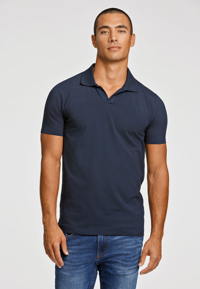 Polo de color azul marino con cuello, mangas cortas y un diseño ajustado. Fabricado con una tela suave con una textura sutil.