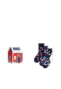 Czerwone pudełko prezentowe stylizowane jak dom z napisem "HAPPY SOCKS"; trzy pary skarpetek z wzorami cukrowych lasek, bałwanków i prezentów w kolorze granatowym i białym.