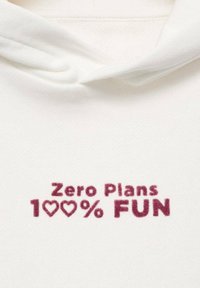 Bela kapuca z mehkim materialom z burgundskimi napisi: "Brez načrtov 100% zabave," okrašena z simboli srca. Preprost in sproščen dizajn.