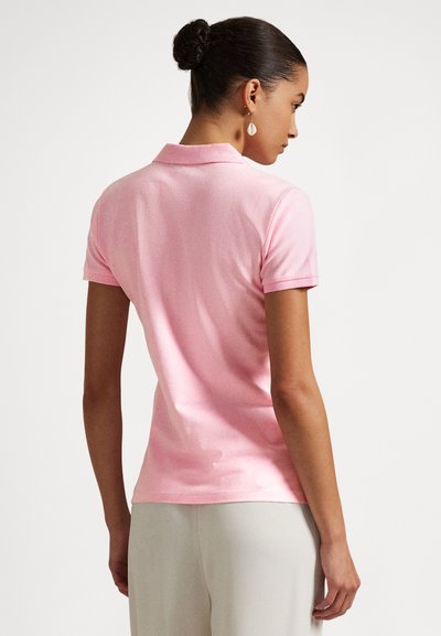 Trumparankovė polo marškinėliai švelnios rožinės spalvos audinyje, turi klasikinį apykaklę ir prigludusią siluetą su lygiu paviršiumi.