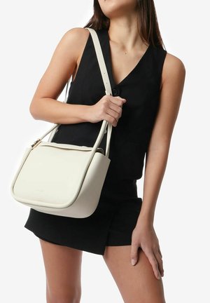 White leather handbag with a curved shape and a magnetic closure. Features a long shoulder strap and minimal hardware. Smooth texture.
