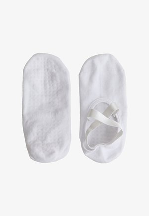 Par hvite slip-on dansegensere, den ene viser teksturert gripe såle, den andre med elastiske stropper over toppen.