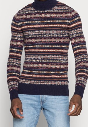 Pull en tricot avec un col haut, présentant un motif rayé multicolore en marine, rouge et beige. Poignets et ourlet côtelés.