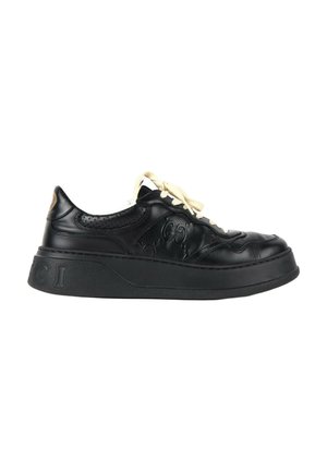 Zapatilla negra de cuero con suela gruesa, cordones blancos, paneles laterales texturizados y diseño en relieve en el costado exterior.