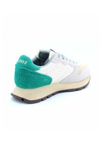 Sneaker mit einer grünen strukturierten Ferse, Obermaterial aus weißem und grauem Stoff, hellbrauner Sohle und dezenten Akzentdetails. Verfügt über Schnürsenkel und Branding.