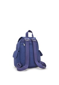 Lila ryggsäck gjord av texturerat tyg, med justerbara remmar, ett huvudfack, två sidofickor och silverfärgade beslag.